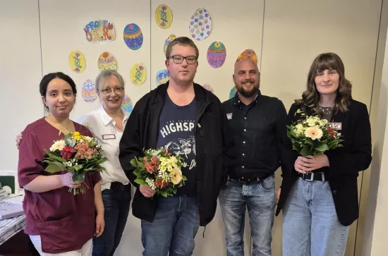 fünf Personen stehen vor einer Wand mit Osterdeko